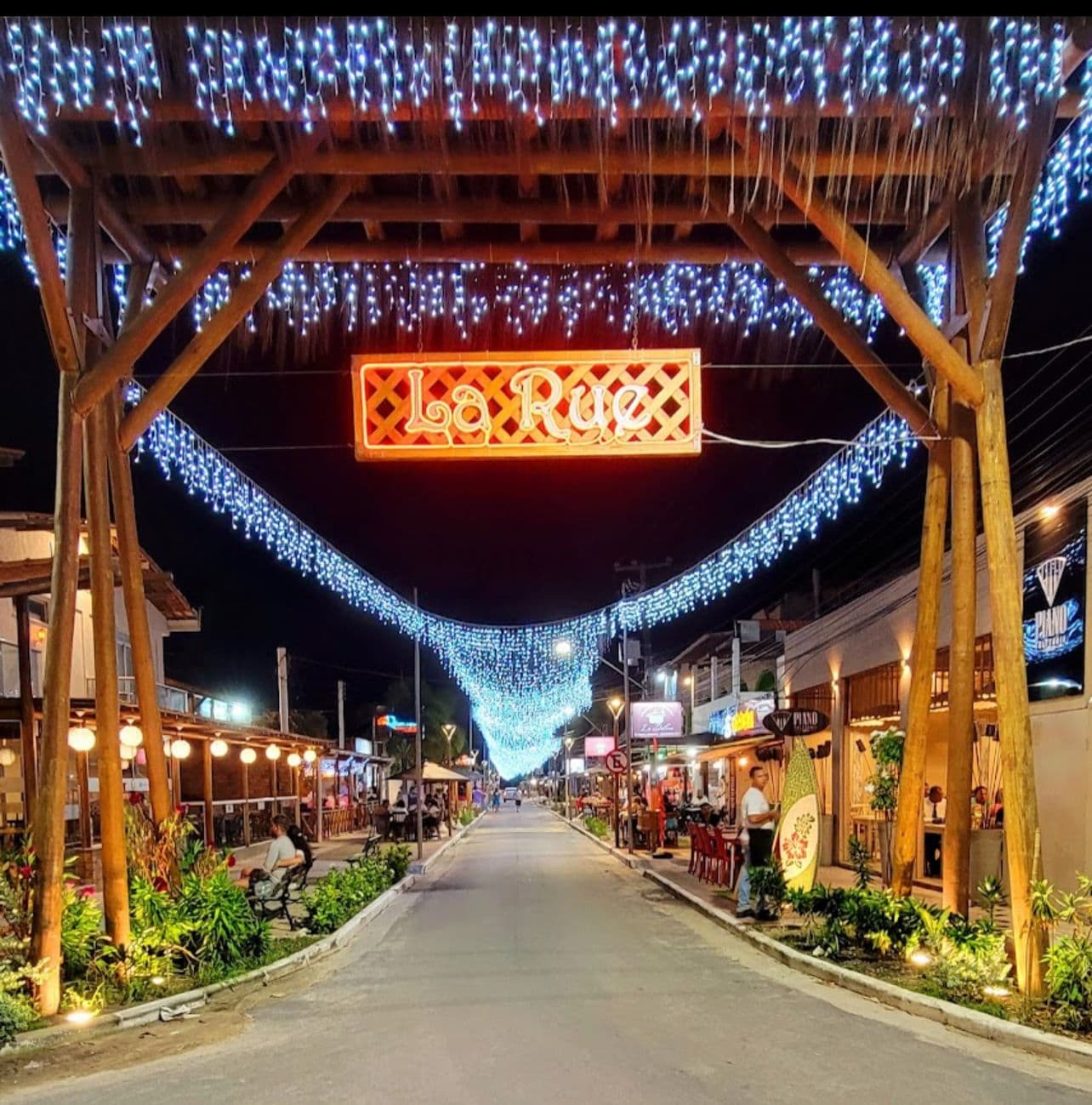 Rua charmosa e iluminada à noite com restaurantes
